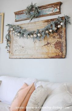 a white couch with christmas decorations on the wall above it and an old frame hanging from the wall