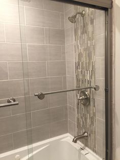 a bath tub sitting next to a shower with a glass door on the side of it