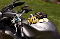 a close up of a motorcycle with gloves on it's handlebars and glove holders