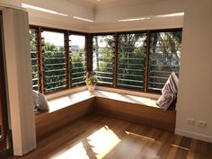 an empty room with wooden flooring and large windows overlooking the trees in the distance