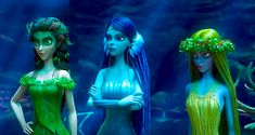 three women dressed in green and blue are standing next to each other with long hair