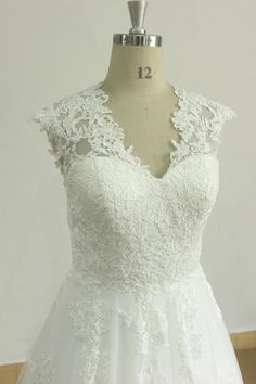 a white wedding dress on a mannequin with an open back and lace detailing