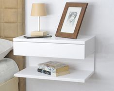 a white shelf next to a bed with a book and lamp on top of it