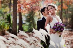 a bride and groom pose for a wedding photo in the woods at their fall wedding