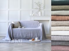 a stack of blankets sitting on top of a wooden floor next to a white couch