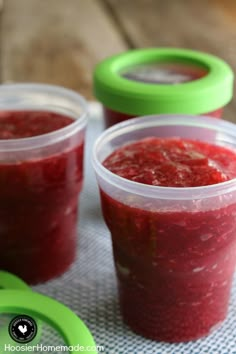 three plastic cups filled with raspberry freezer jam on top of a table