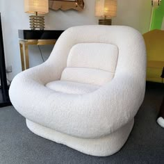 a white chair sitting in front of a mirror on top of a floor next to a lamp