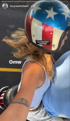 a woman riding on the back of a motorcycle with an american flag painted on her helmet