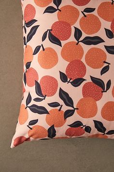 an orange and black pillow with leaves on it's side, against a gray background