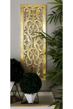 an ornate gold wall hanging next to a potted plant