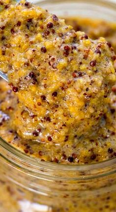 a spoon with some food in it on top of a glass jar filled with something