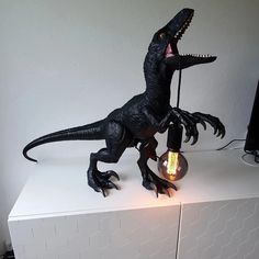 a toy dinosaur with its head turned upside down, holding a light bulb in it's mouth