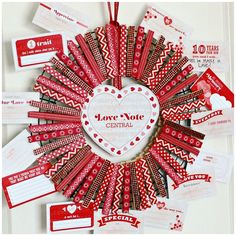 a wreath made out of red and white paper with some tags attached to the front