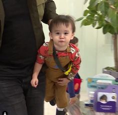 a little boy is holding onto his father's hand as they walk through an airport