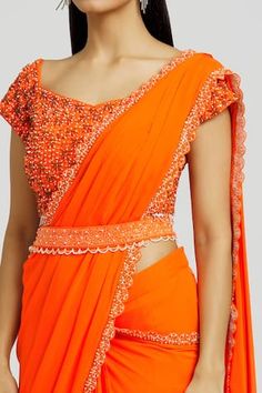 Orange saree with beads and cutdana embroidered borders. Comes with a blouse and a belt.
Components: 3
Pattern: Embroidered
Type Of Work: Beads, Cutdana
Neckline: V Neck
Sleeve Type: Short
Fabric: Silk, Georgette
Color: Orange
Other Details: 
Attached lining
Length:
Saree: 43 inches
Blouse: 14 inches
Note: The fabric is silk blend and not pure silk.
Occasion: Wedding - Aza Fashions Orange Saree, Beaded Neckline, Embroidered Silk, Pure Silk, Aza Fashion, Custom Made, Blouses For Women, Types Of Sleeves, V Neck