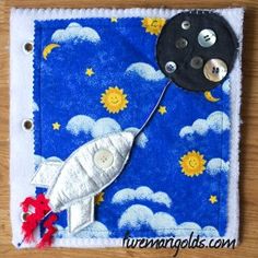 an image of a rocket ship made out of felt and buttons on a piece of cloth