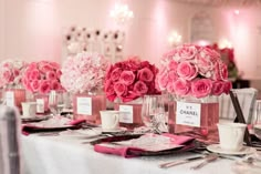 pink flowers are in vases on a table with place cards and silverware for guests to eat