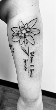 a black and white photo of a person with a flower tattoo on their leg that says,