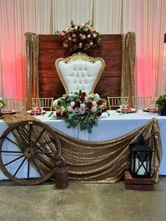 a white chair sitting on top of a table next to a wooden wheel and flowers