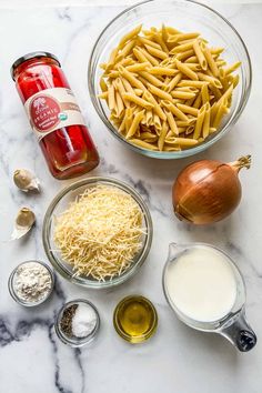 ingredients to make pasta in bowls on a marble counter