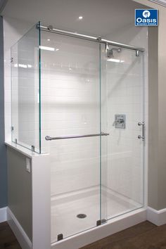 a walk in shower sitting inside of a bathroom next to a white wall and wooden floor