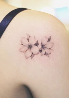 the back of a woman's shoulder with flowers tattooed on her left side ribcage