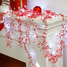 christmas decorations on the mantle in front of a fire place with red and white balls