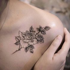 a woman's shoulder with a rose and leaves tattoo on her left side breast