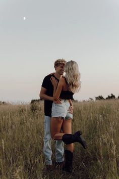 a man and woman standing in tall grass