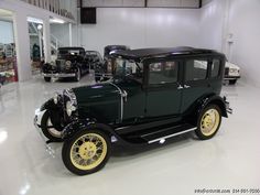 an old black car is parked in a showroom