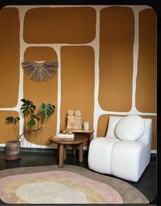 a living room with an orange wall and white chair next to a potted plant