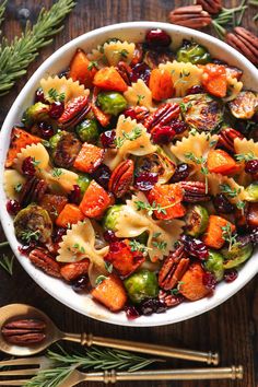 a white bowl filled with pasta and veggies on top of a wooden table