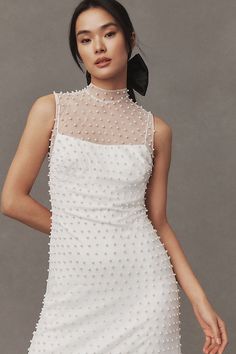 a woman is wearing a white dress with pearls on it