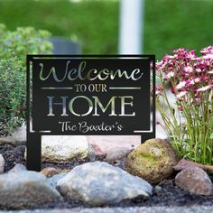 a welcome sign in front of some rocks and flowers