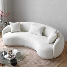 a white couch sitting on top of a wooden floor next to a glass coffee table