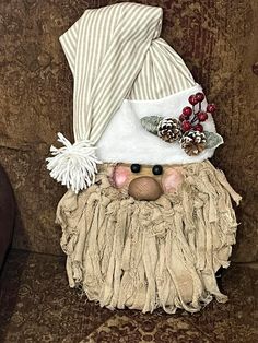 a stuffed animal wearing a hat and scarf sitting on a brown couch next to a pine cone