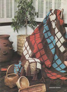 there is a crocheted blanket on the floor next to baskets and potted plants