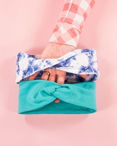 a woman's hand holding onto a blue and white tie - dyed clutch bag