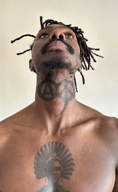 a man with dreadlocks and tattoos on his chest