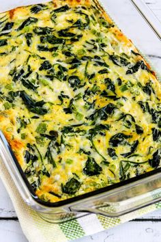 spinach and cheese casserole in a glass dish on a white wooden table