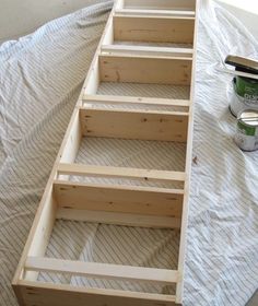 a wooden boat sitting on top of a bed next to a paint can and brush