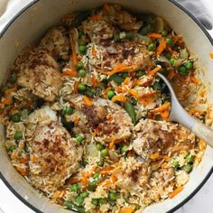 a pot filled with rice and meat covered in peas, carrots and other veggies