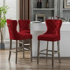 two red velvet bar stools in front of a white counter