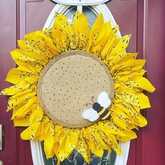 a sunflower wreath with a bee on it hanging from the front door to welcome guests