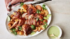 a white plate topped with chicken and potatoes next to a cup of green juice on a table