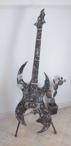 a metal guitar sculpture sitting on top of a tiled floor