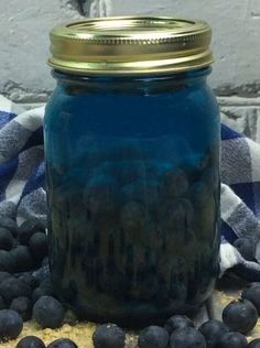 a blue jar filled with blueberries sitting on top of a table next to a plaid cloth