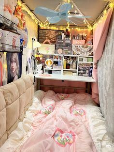 a bed with pink sheets and pillows in a room filled with lights, posters and pictures