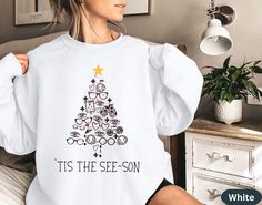 a woman is wearing a white sweatshirt with a christmas tree on it and the words tis the