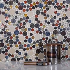 a wall with many different colored circles on it and a metal canister next to it